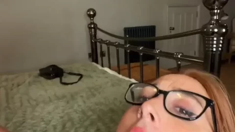 Redhead with glasses gives deepthroat blowjob in bedroom POV