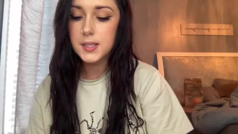 Young Woman with Dark Hair and Nose Piercing in Bedroom