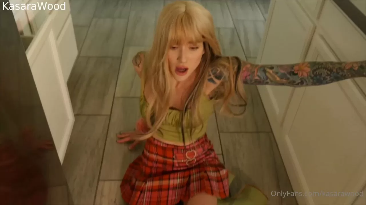 Blonde with arm tattoos drinks and strips in kitchen