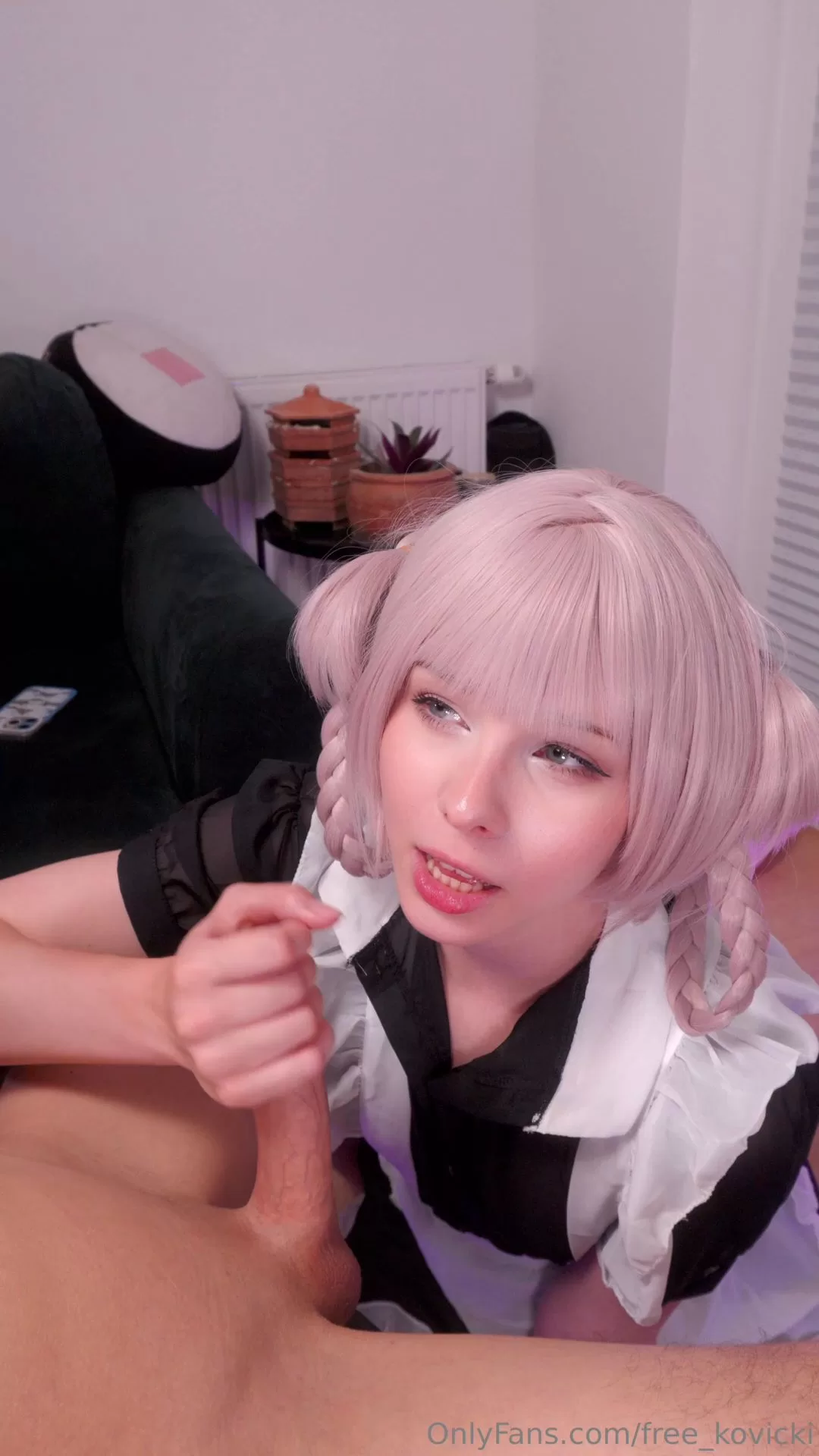 Pink-haired girl with bangs and braids gives blowjob on black couch