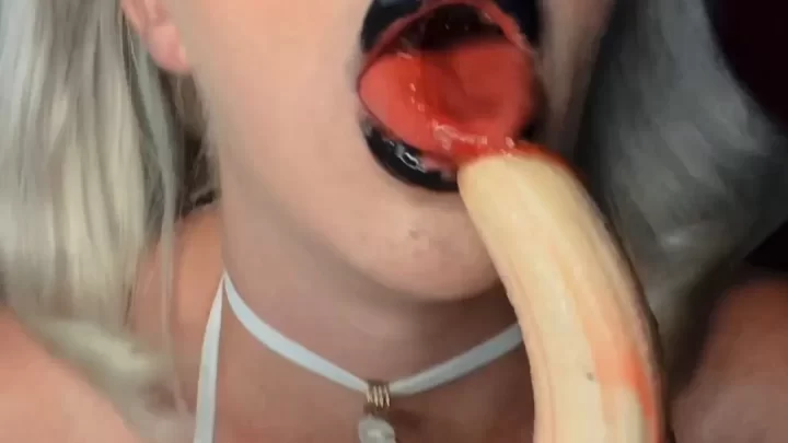 Blonde in white bikini sucks banana with ketchup, heavy makeup close-u