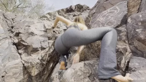 Blonde in leggings climbs rocks outdoors, flashes skin in alcove