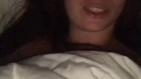 Brunette girl lies in bed, makes selfie