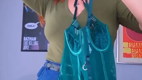 Redhead tries on teal corset