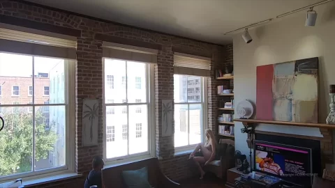 Blonde girl sits on chair, gets company on couch