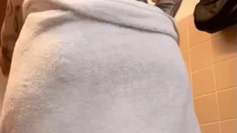 Tattooed brunette girl plays with towel in bathroom