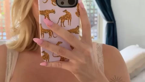 Blonde girl covers face with phone while exposing breasts