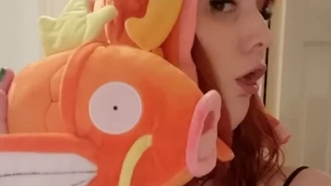 Redhead girl plays with orange fish hat