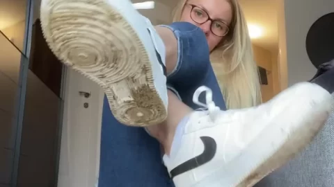 Blonde girl sits on floor, plays with legs