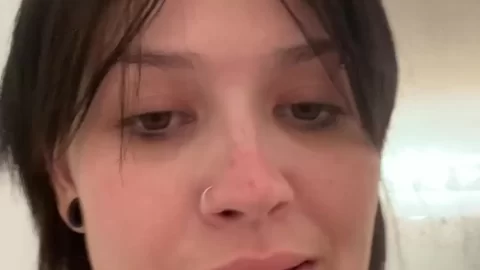 Brunette with tattoos talks to camera in bathroom