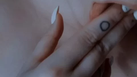 Slim 20s girl with tattoos on finger & freckles touches neck