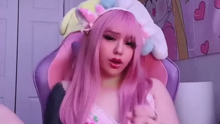 Pink-haired girl talks and gestures in bedroom