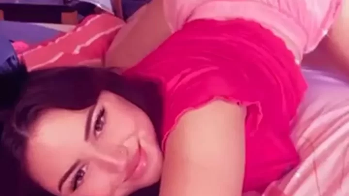 Brunette with tattoo lays on stomach, looks at camera