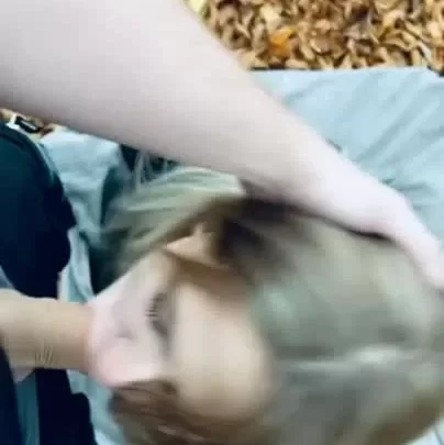 Blonde woman restrained outdoors by muscular guy