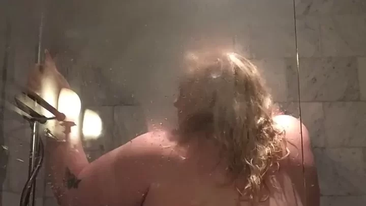 Blonde woman showering, tattoo on arm