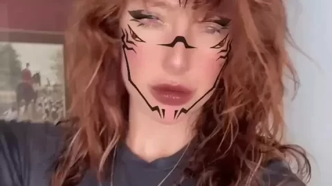 Redhead with face tats poses and touches hair
