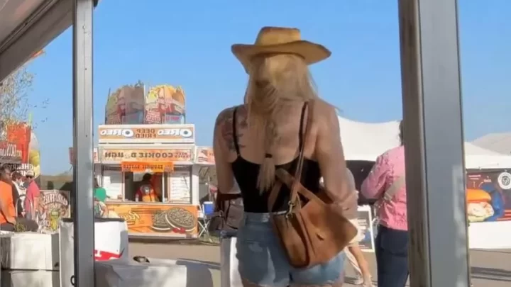 Blonde girl with tattoos walks around outdoor festival