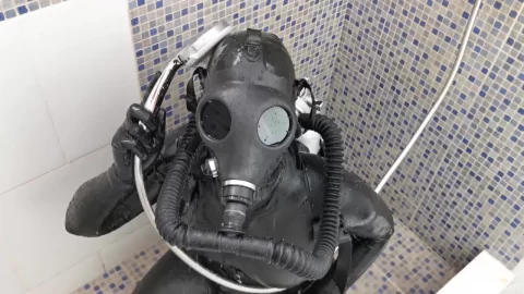 Slim girl in black latex bodysuit and gas mask fucks herself in shower