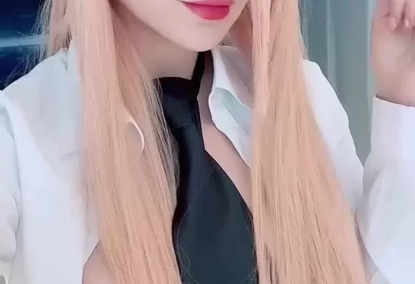 Blonde Asian girl with red horns and eyes poses and touches hair