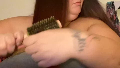 Brunette with tattoo and glasses brushes hair