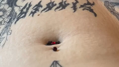 White guy with tattoos uses red ball on stomach
