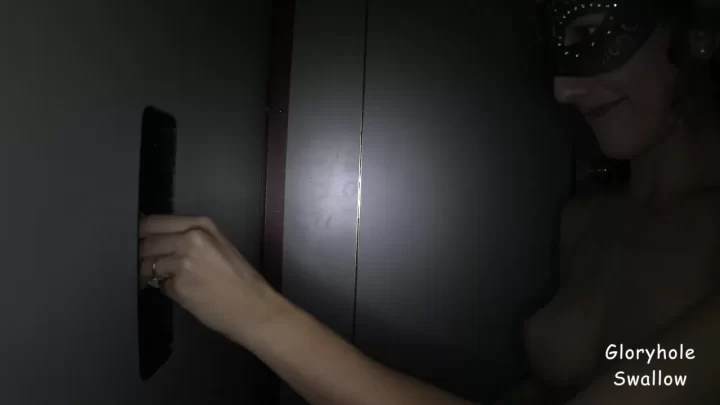 Slim brunette in masquerade mask gives blowjob through glory hole