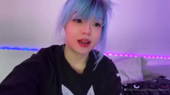 Petite white girl with blue hair and pierced teeth talks to camera