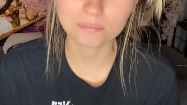 Blonde girl sits on couch, looks at camera