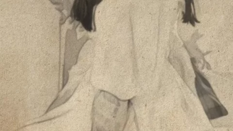 Mature Asian Woman Sitting on Chair, Looking Over Shoulder
