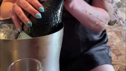 Blonde girl pops champagne cork in hotel room