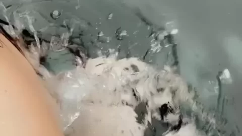 Brunette girl soaks in bathtub, plays with soap