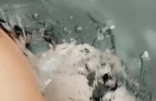 Brunette girl soaks in bathtub, plays with soap
