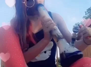 White girl with tattoos smokes bong outdoors