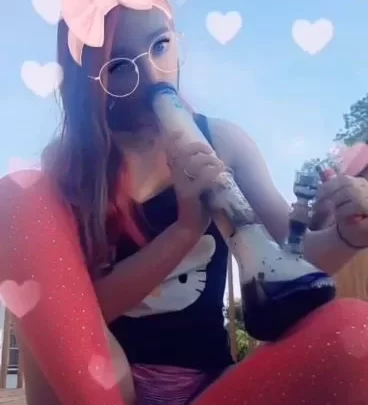 White girl with tattoos smokes bong outdoors