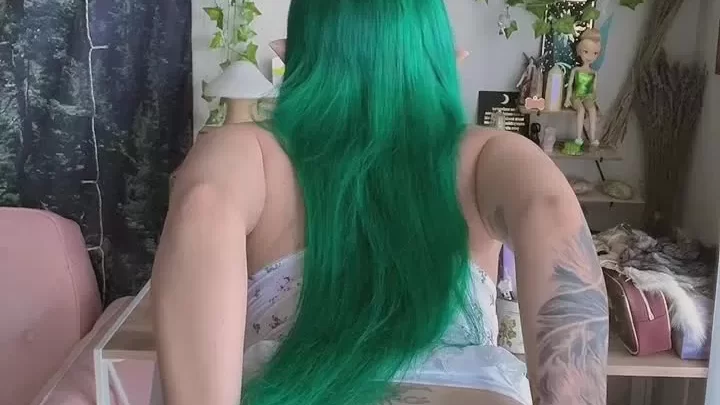 Green Haired Girl Sits on Pink Chair, Looks Back