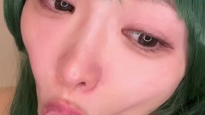 Asian girl with green dress gives herself a blowjob