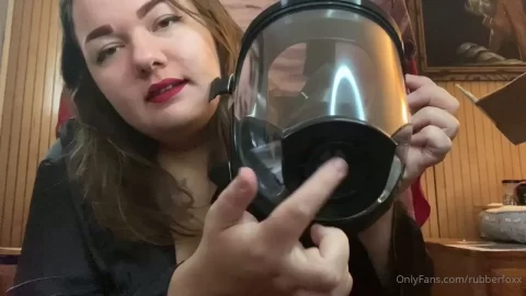 Brunette in red lipstick tries on gas mask