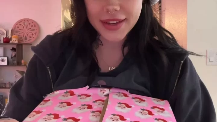 White girl with dark hair and tattoos opens pink Santa gift
