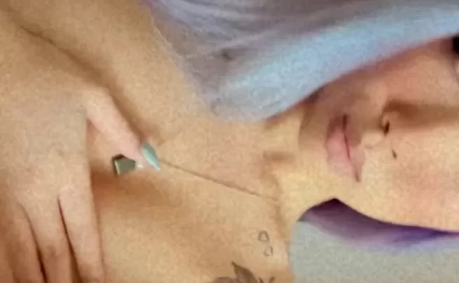 Slim girl with tattoo touches shoulder in bathroom